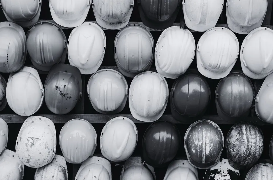 An overhead view of white construction hard hats, in black and white.