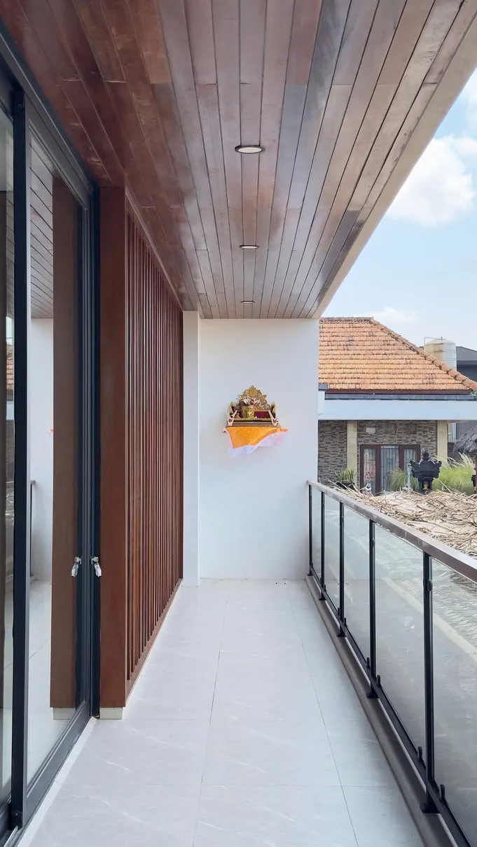 A balcony with a timber ceiling, glass balustrade and sliding glass doors.