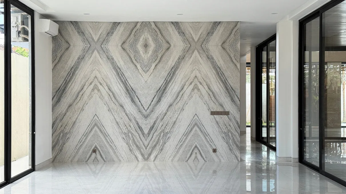 An open room with symmetrical marble wall patterns and black-framed glass doors.