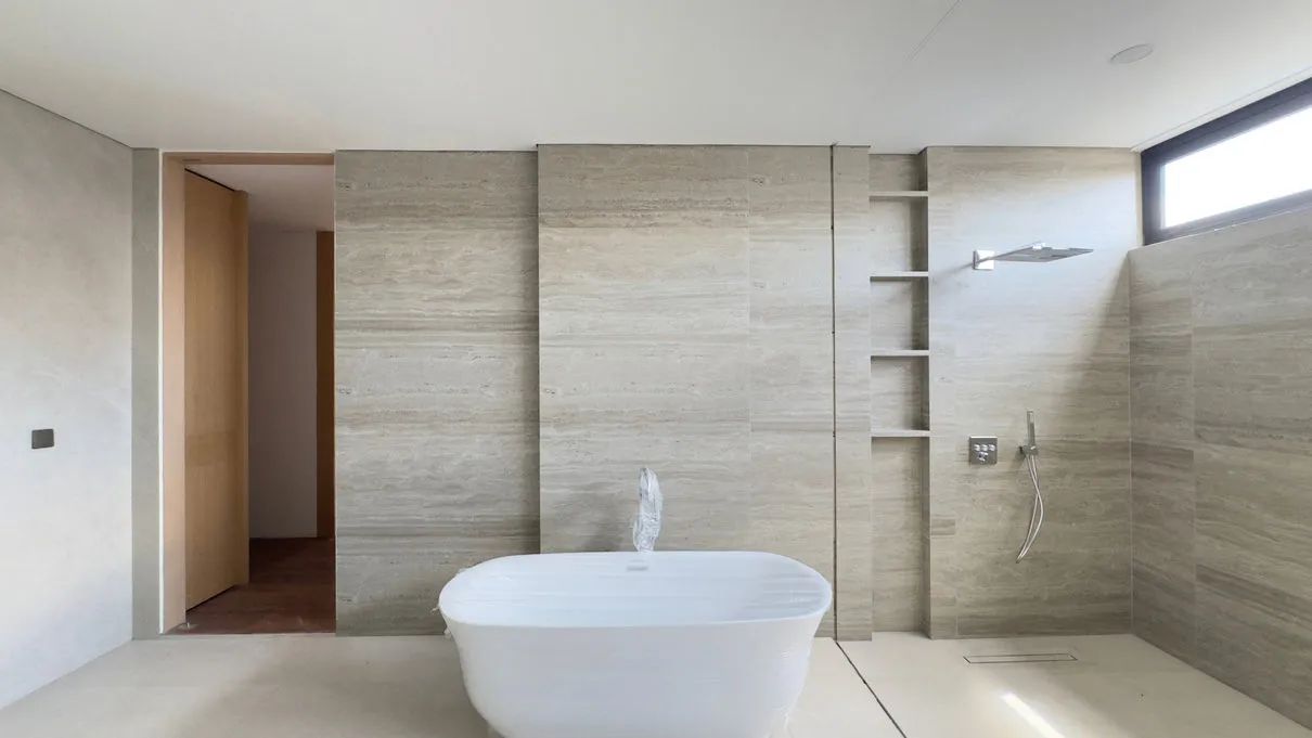 A bathroom with a freestanding bathtub and natural stone walls.