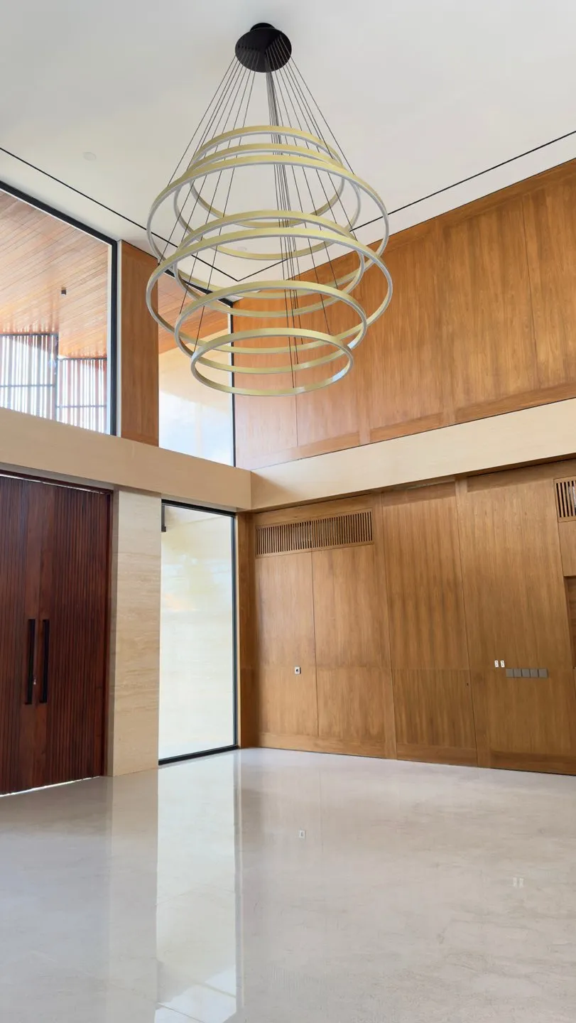 A double-height space with tiered pendant lights and timber panelling.
