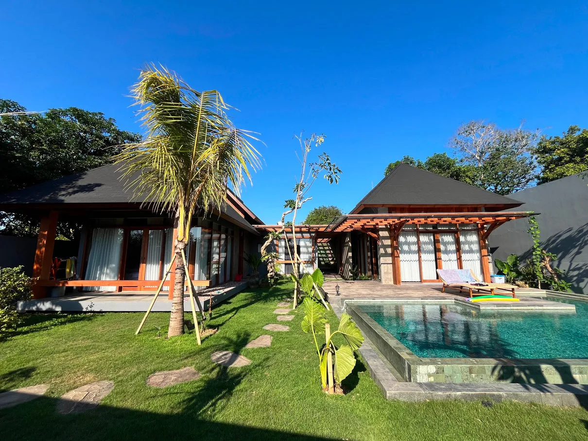 A house with timber and black pitched roofs, a swimming pool and lawn.