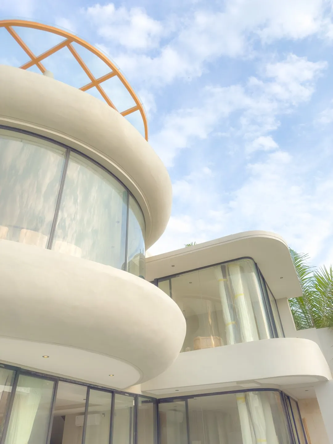 A curved white building with glazed windows against a blue sky.