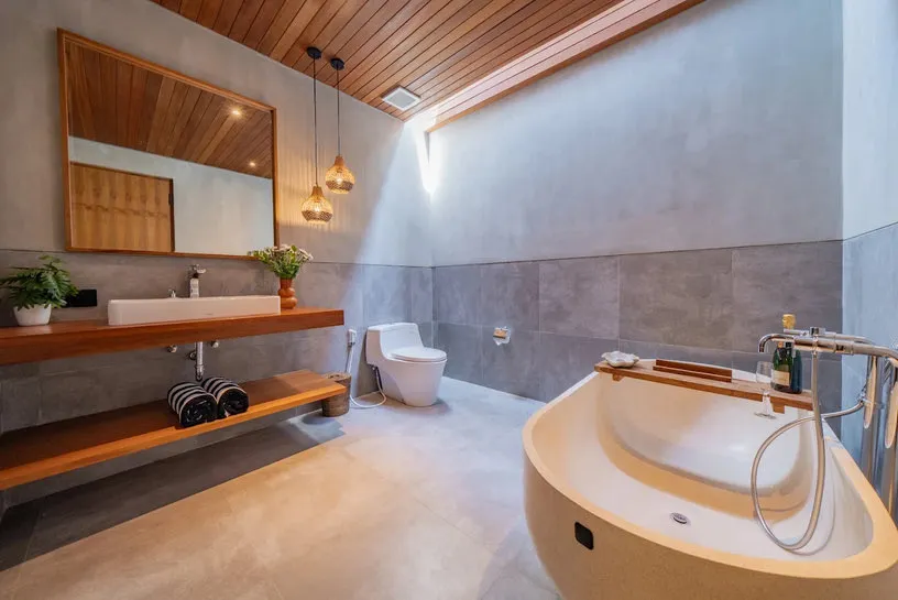 A bathroom with a timber ceiling, bathtub and mirror.